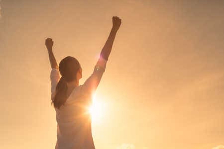 Affirmationen für den Tag Frau streckt Hände zur Sonne Ein neues Leben